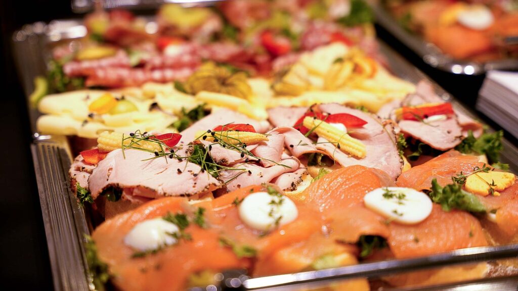 Eine Platte mit leckeren Köstlichkeiten, bestehend aus belegten Brötchen mit Wurst, Käse, Eiern, Gemüse und Kräutern - perfekt arrangiert für das Firmencatering oder den Partyservice bei jedem Buffet oder besonderen Anlass.